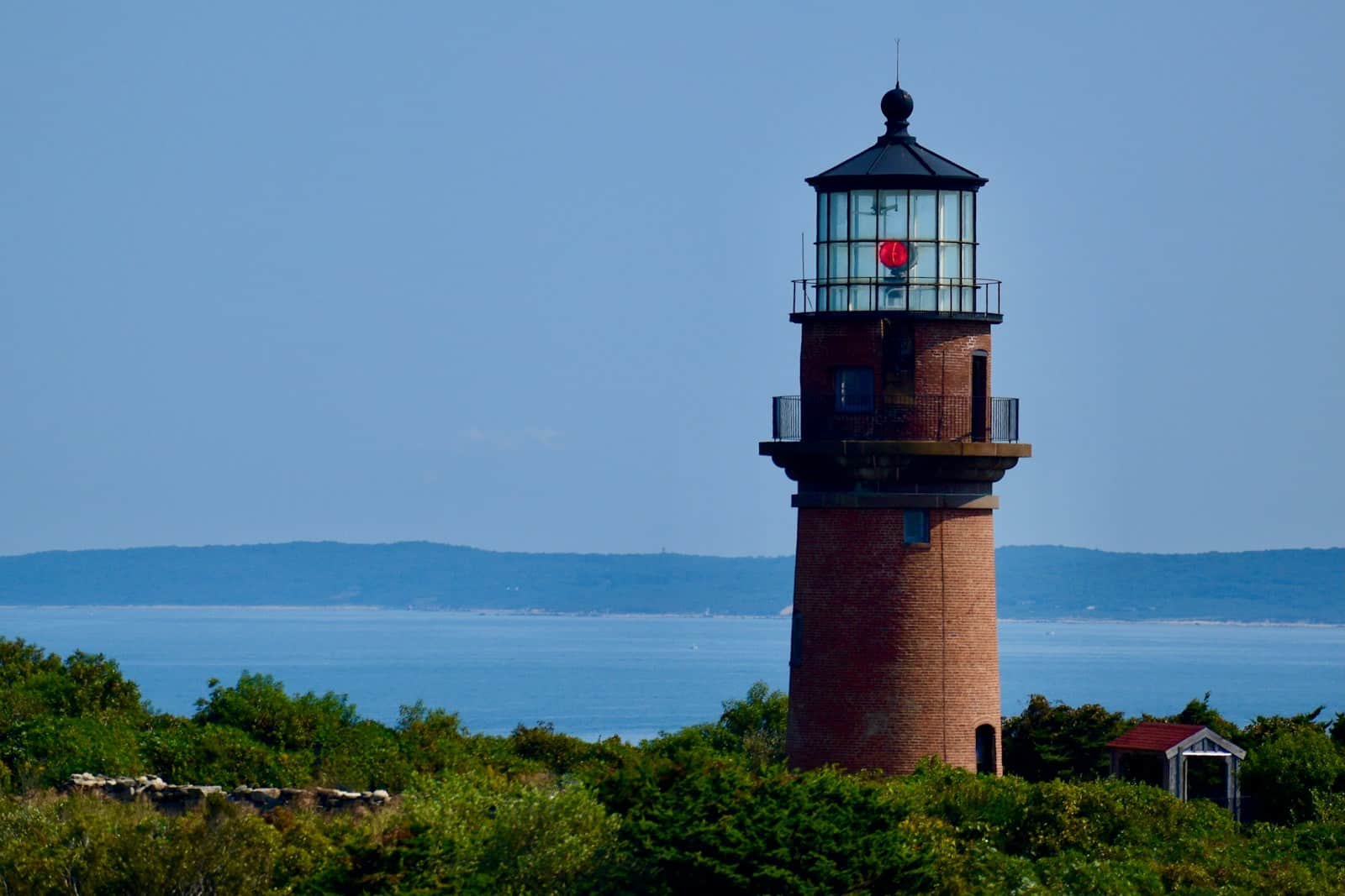 A red and white light house sitting on top of a lush green hillside